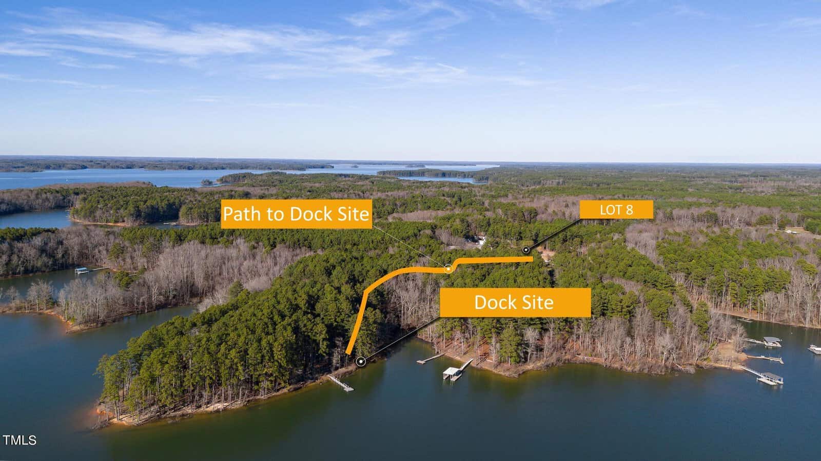 Aerial view of a lake near Manson, surrounded by forest. An orange line shows the "Path to Dock Site" leading to a "Dock Site" on the water. "Lot 8 S Piney Grove Road" is labeled nearby, with multiple small docks and boats visible along the shoreline.