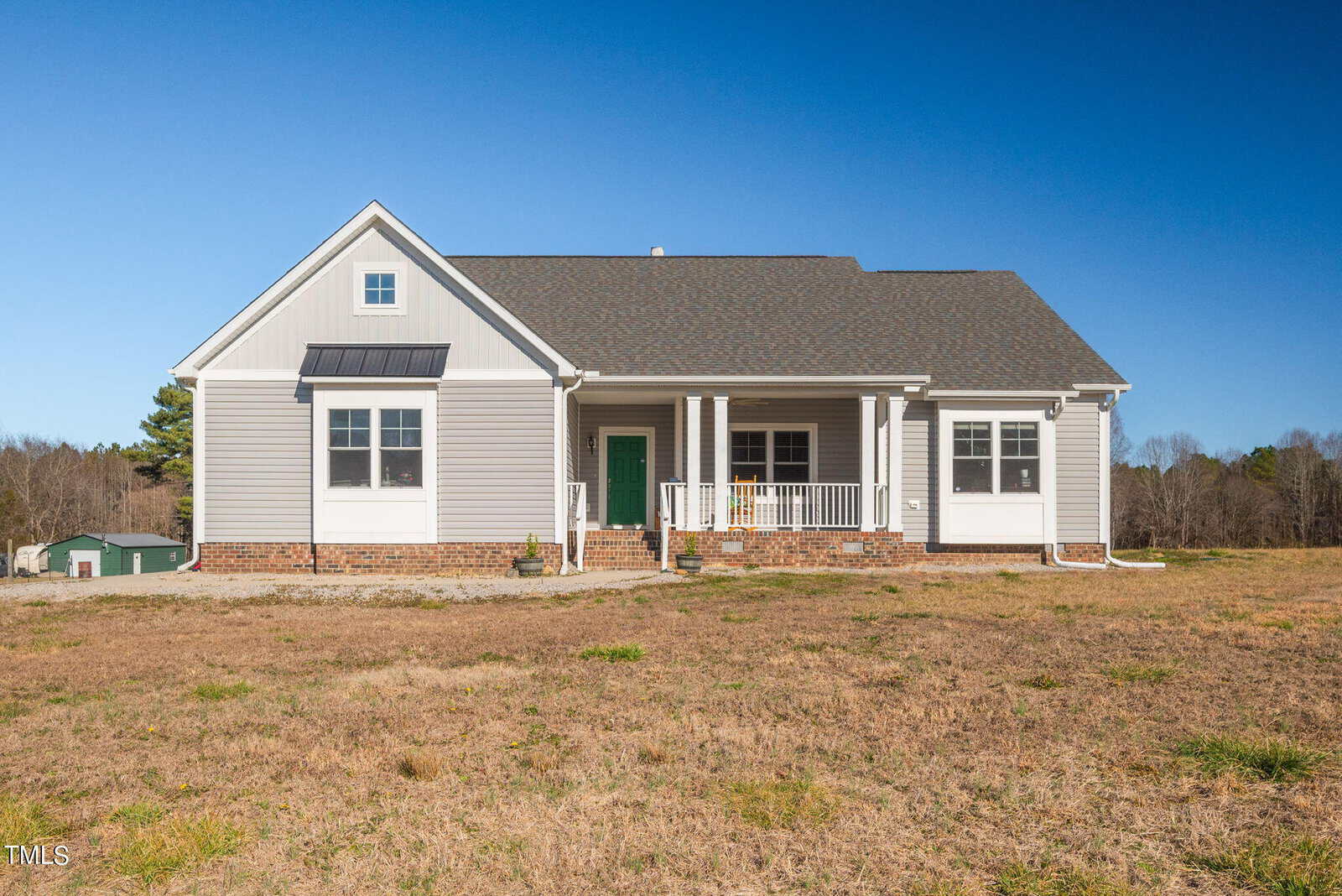 A new single-story house at 1428 Spring Valley Lake Road, Henderson NC, with a pitched roof, white siding, green shutters, and a front porch. The house is situated on a