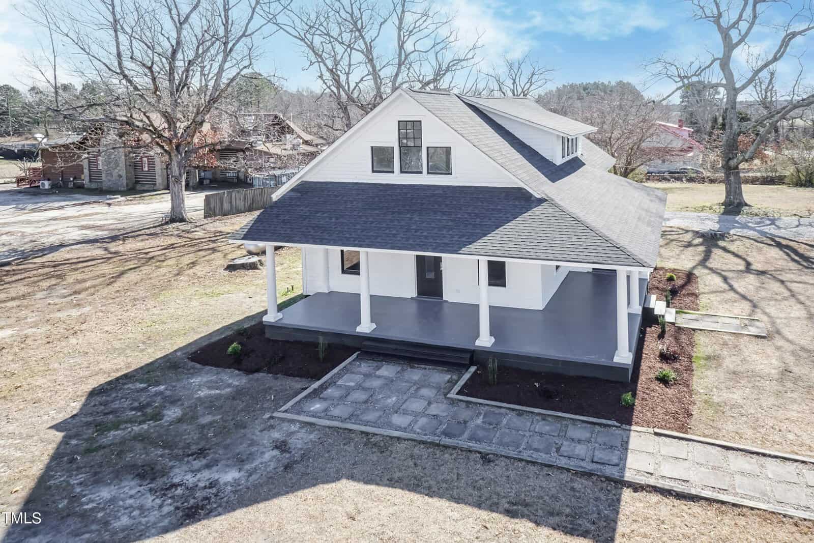 Located at 156 Walnut Street, Middleburg, this charming two-story white house features a black roof and a spacious front porch. The yard is beautifully landscaped with a pathway leading to the entrance, and leafless trees surround the property, signaling a winter or early spring setting.