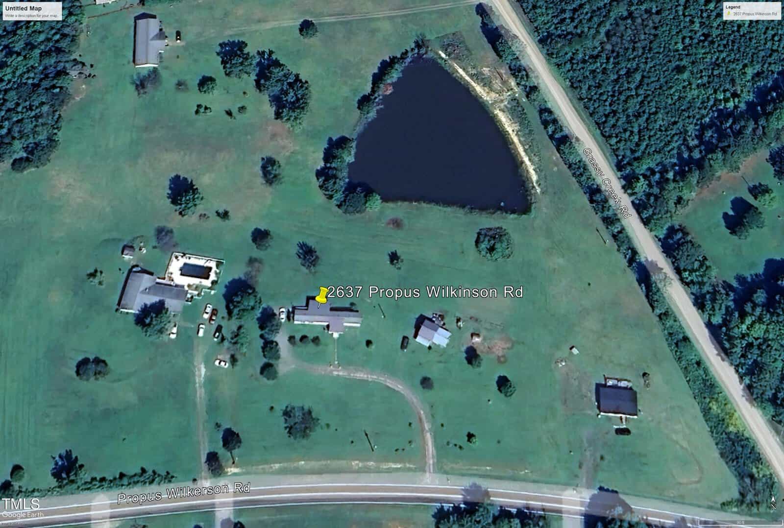 Aerial view of a rural property with green fields, several buildings, a pond, and a road labeled "2637 Propus Wilkinson Rd." The area is surrounded by trees, and the landscape is open with scattered trees and structures.