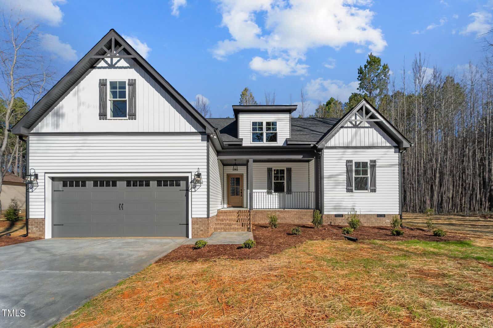 Nestled at 1151 Shonele Lane, this modern two-story house boasts white siding and dark trim. With a gabled roof, a two-car garage adorned with dark doors, and a cozy porch, it stands gracefully against a backdrop of trees under a partly cloudy sky in the picturesque town of Stem.