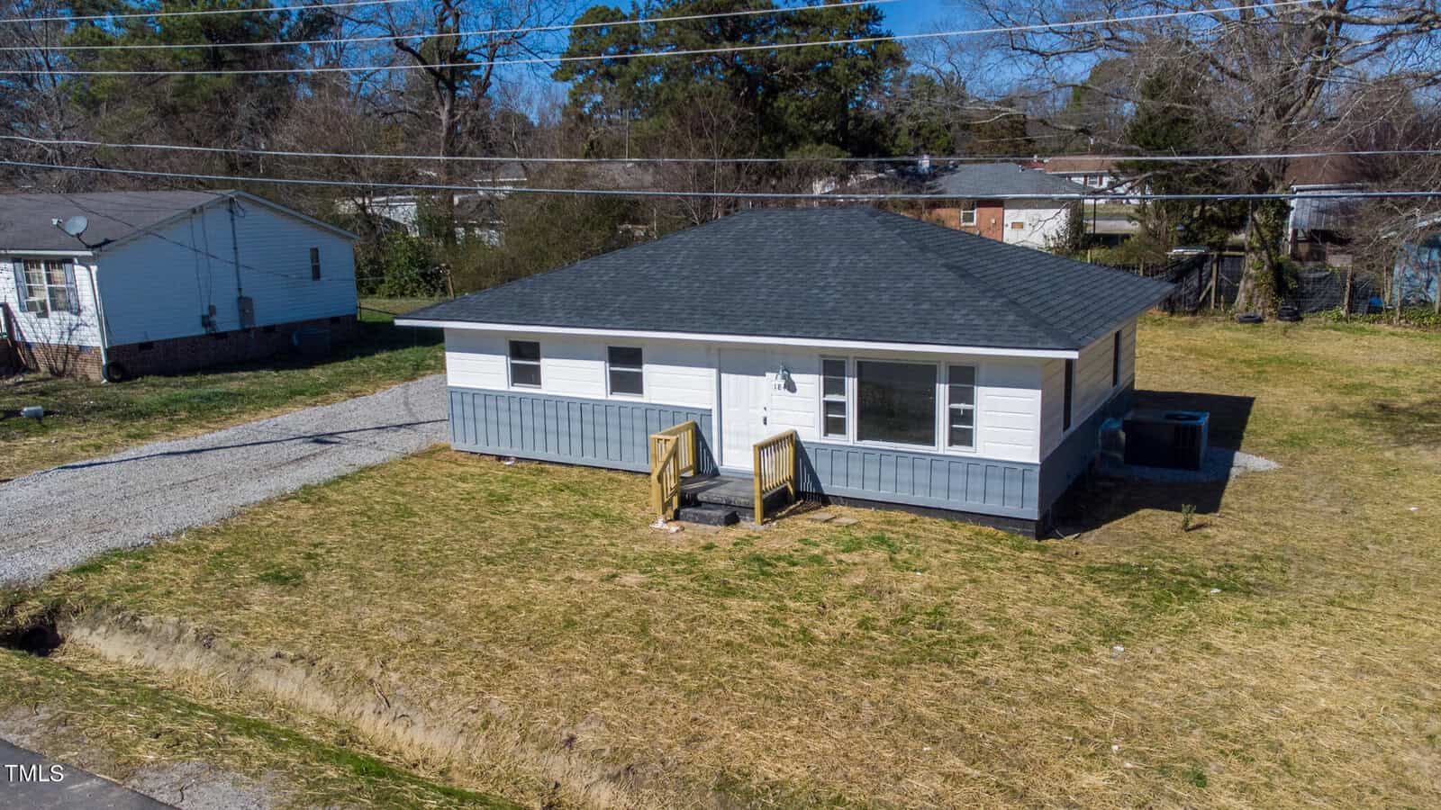 Aerial view of a small, single-story house located at 1841 Garland Street in Henderson, NC, with a gray roof and white siding, featuring front steps. The house is surrounded by a