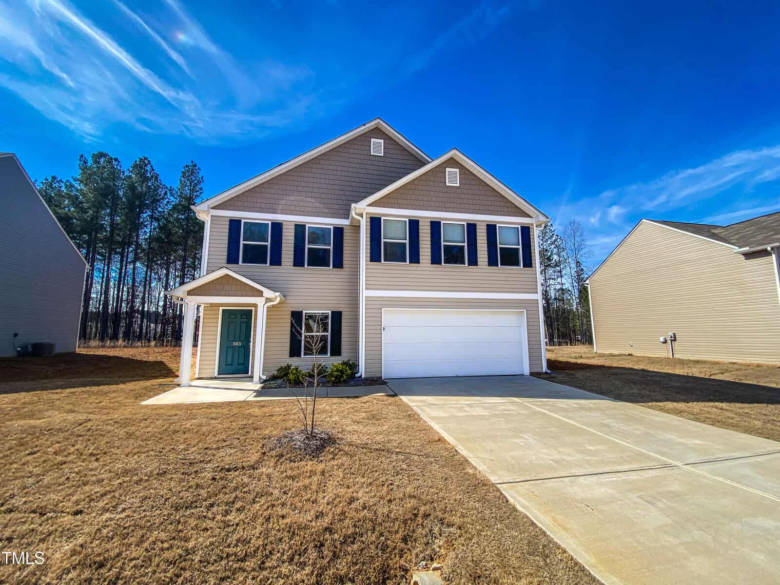 A two-story suburban home with a two-car garage and a pale blue entrance door, situated under a clear blue sky.