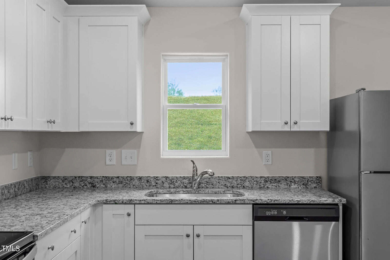 A modern kitchen with white cabinets, a granite countertop, and stainless steel appliances. There is a window above the sink, allowing natural light to brighten the room.