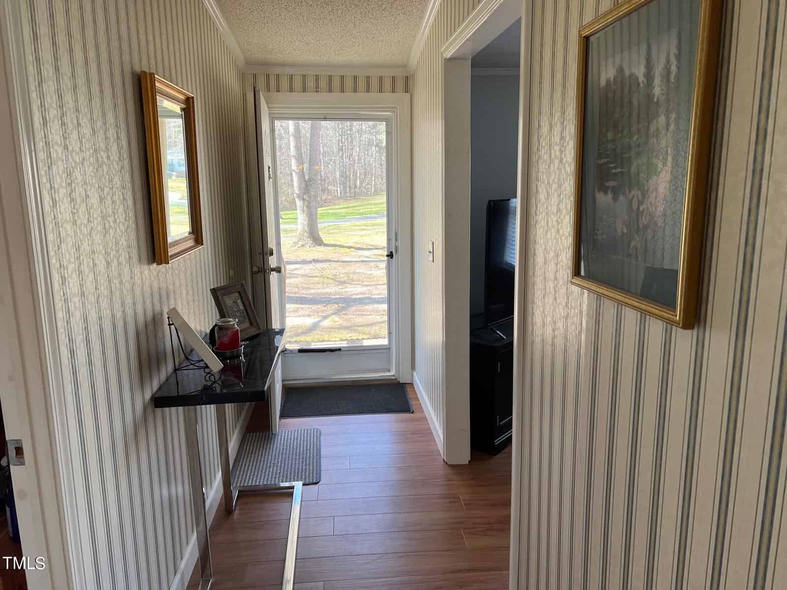 A hallway with a door and a mirror.