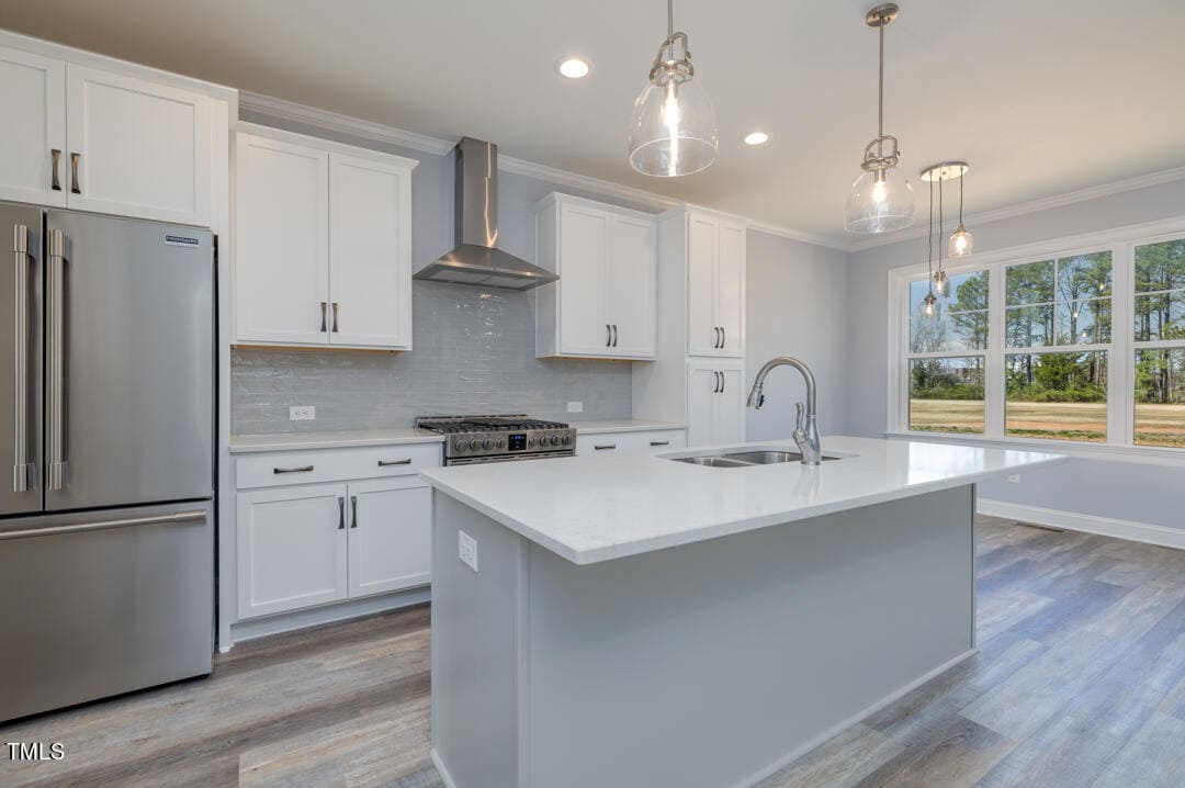 Modern kitchen interior with white cabinetry, stainless steel appliances, an island with a sink, and pendant lighting.