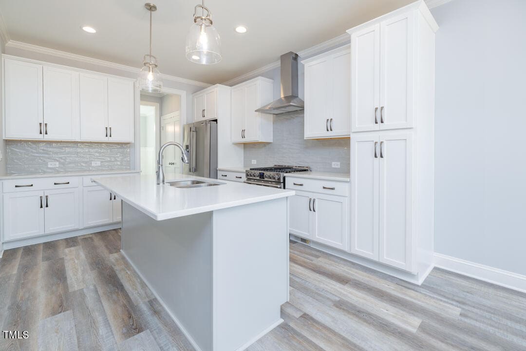 A modern kitchen featuring white cabinetry, stainless steel appliances, and light wood flooring.