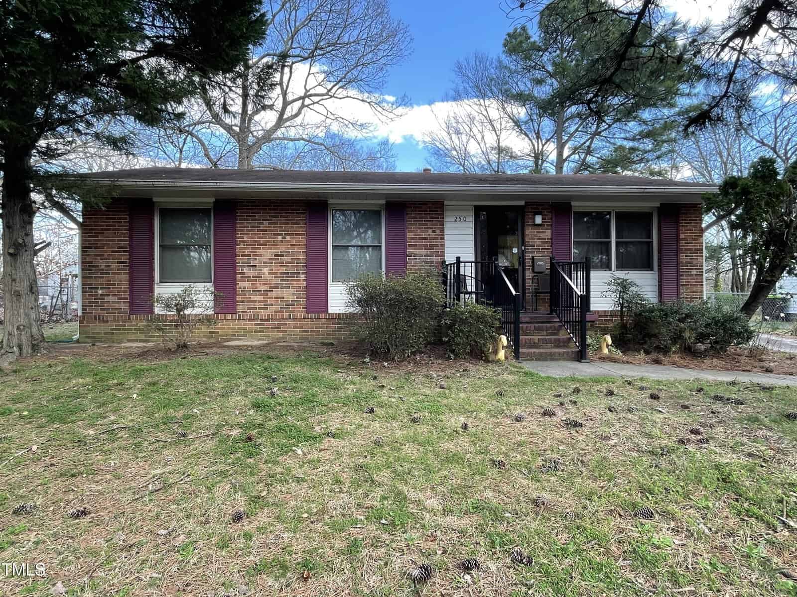 A single-story brick house at 250 N Pinkston Street, Henderson NC, with white siding under a clear sky. The house features a central door flanked by two windows and a small front lawn
