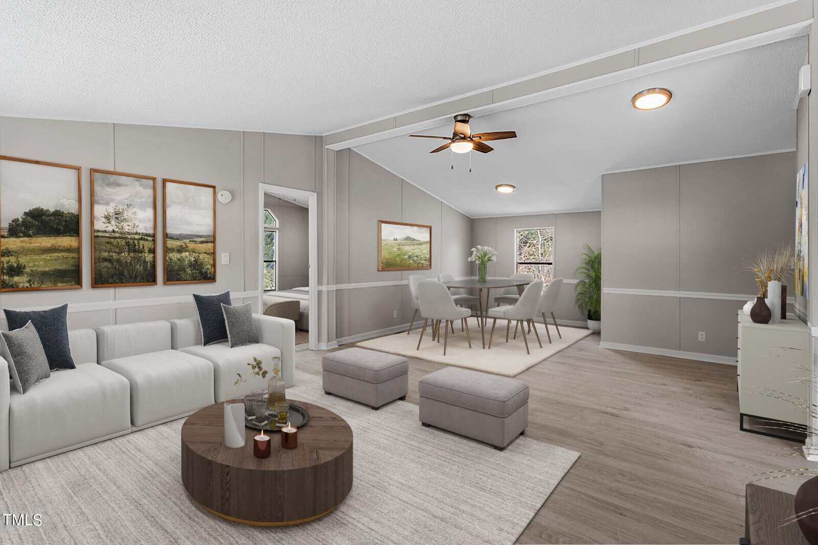 Modern living room at 858 Foster Road, Henderson NC with large grey sectional sofa, round wooden coffee table, and matching ottomans. The room features a dining area with a table set for four