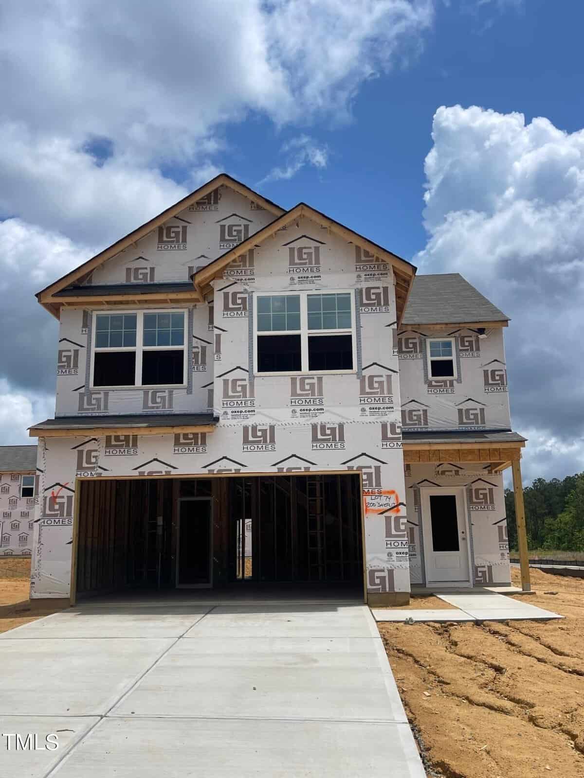 Located at 200 Shelfit Trail, this newly constructed two-story house in Oxford boasts wrap-around construction material and expansive windows. A partly cloudy sky hovers over the site, where ongoing development hints at the promise of a flourishing neighborhood.