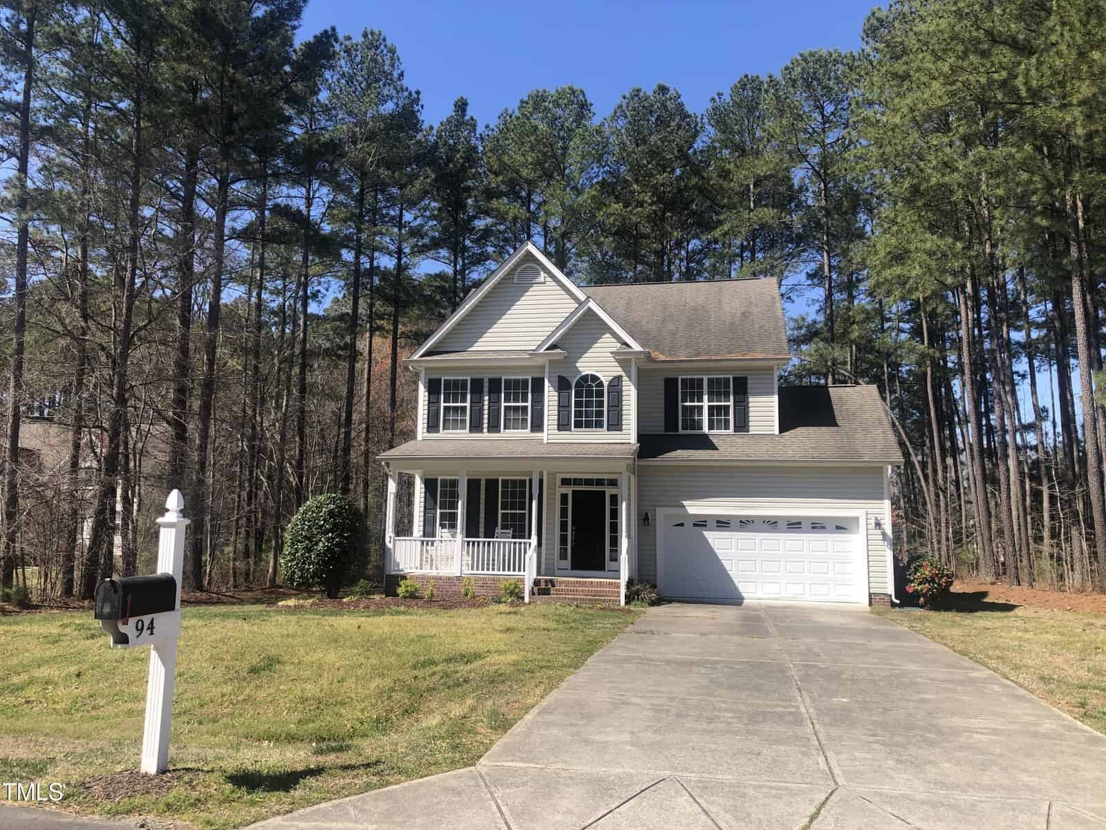 A two-story suburban house at 94 S Cinnebar Court in Henderson, NC, with a white facade and dark shingled roof, featuring a garage, front porch, and a mailbox numbered