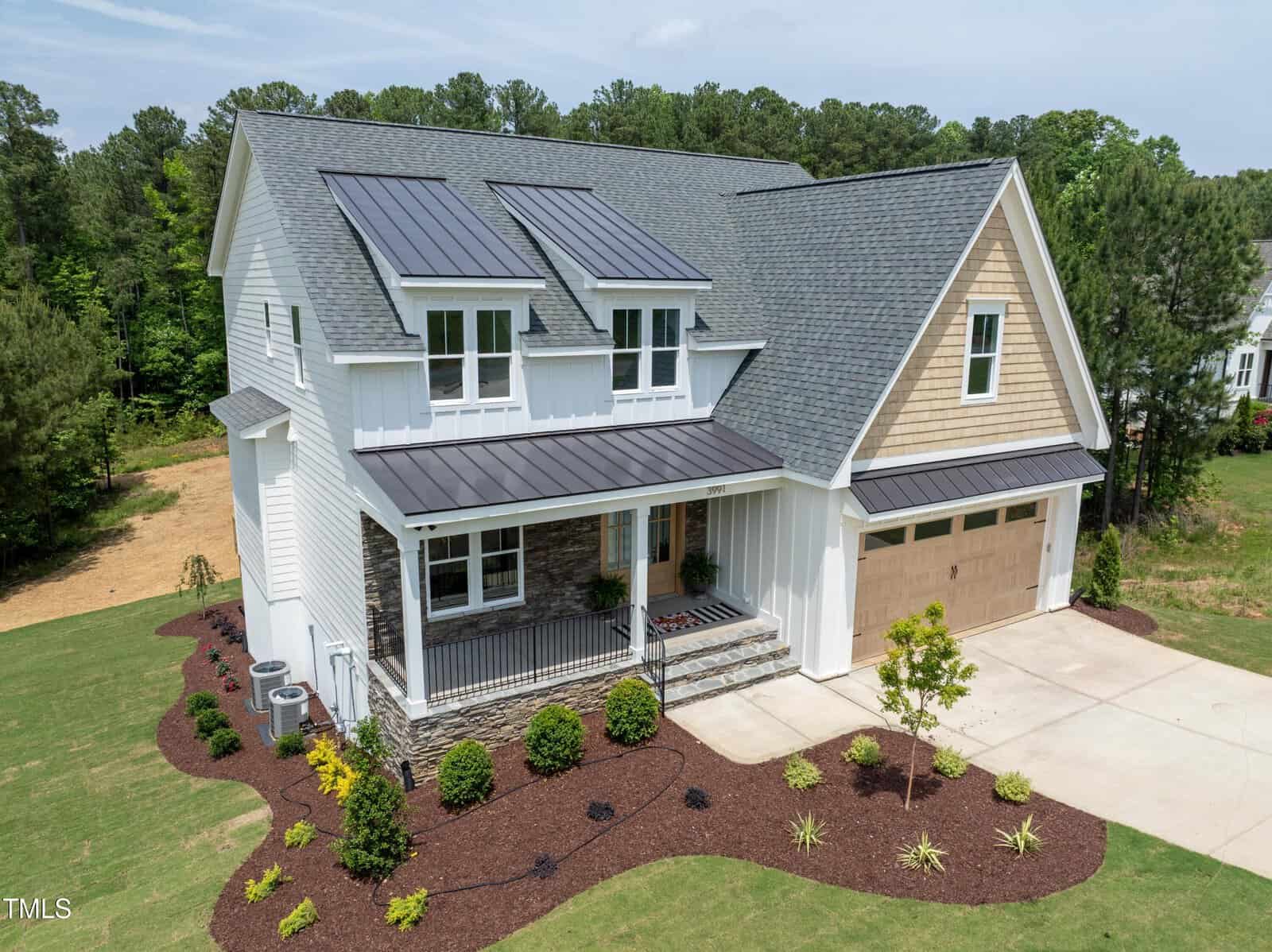 Located at 3991 Hope Valley Drive in the scenic Wake Forest area, this modern two-story house boasts solar panels on the roof. With white siding and stone accents, it includes a two-car garage, covered porch, and a landscaped front yard framed by neatly trimmed hedges and lush greenery.