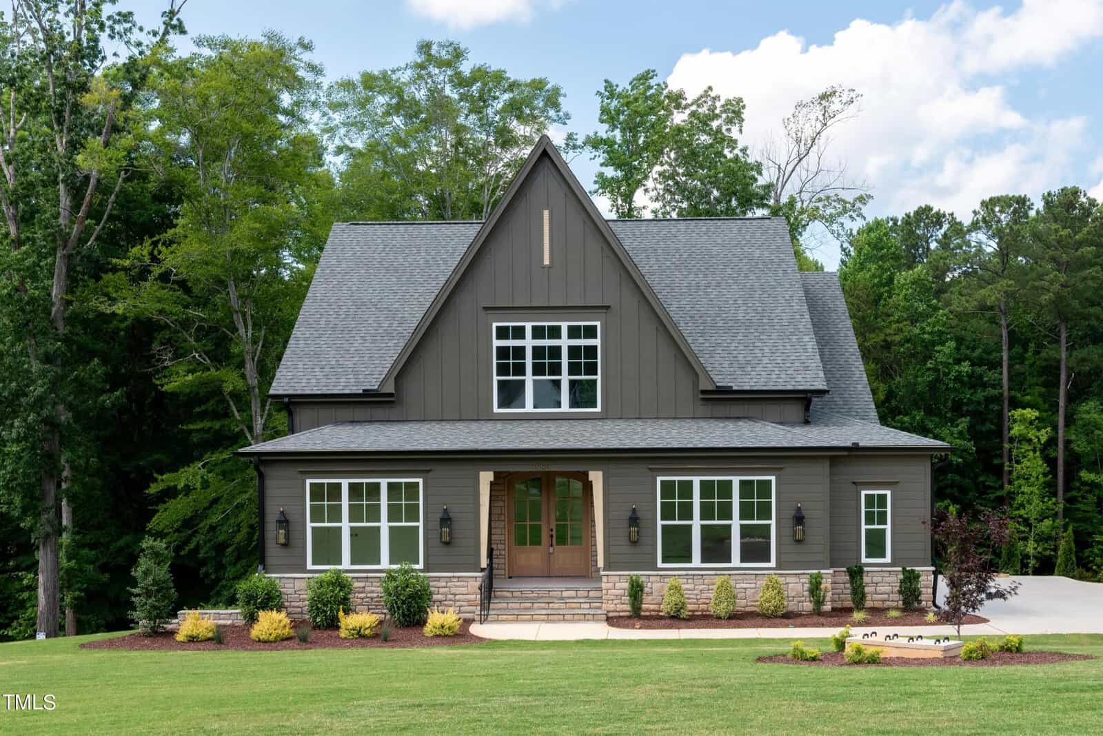 Located at 3985 Hope Valley Drive in Wake Forest, this charming two-story house with dark gray siding and a sloped roof is surrounded by lush green trees. The front yard boasts a well-kept lawn and small shrubs near the entrance, all under a clear blue sky.