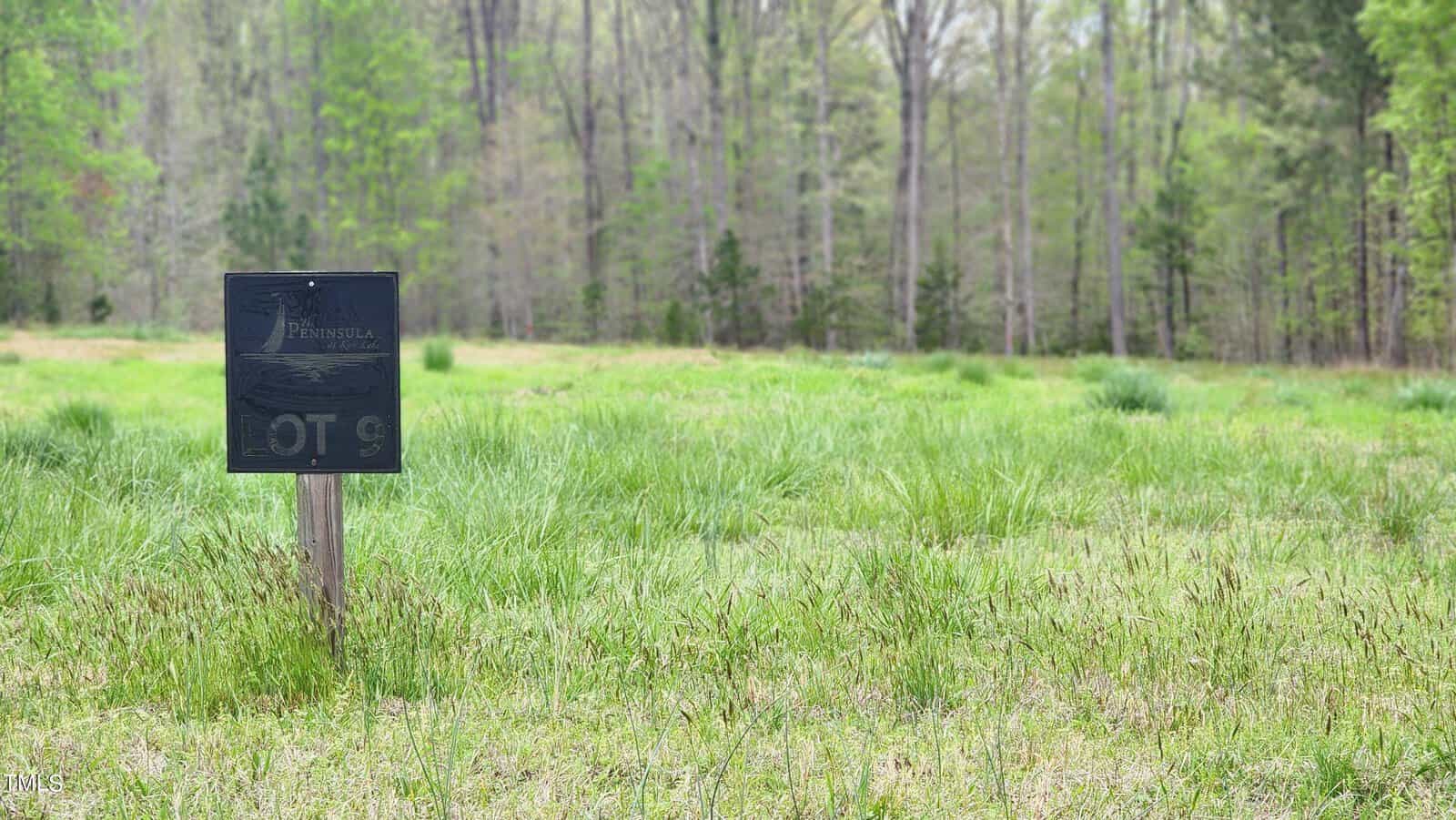A serene green landscape in Henderson NC, with a vibrant meadow, trees in the background, and a sign labeled "Waterstone" in the foreground.
