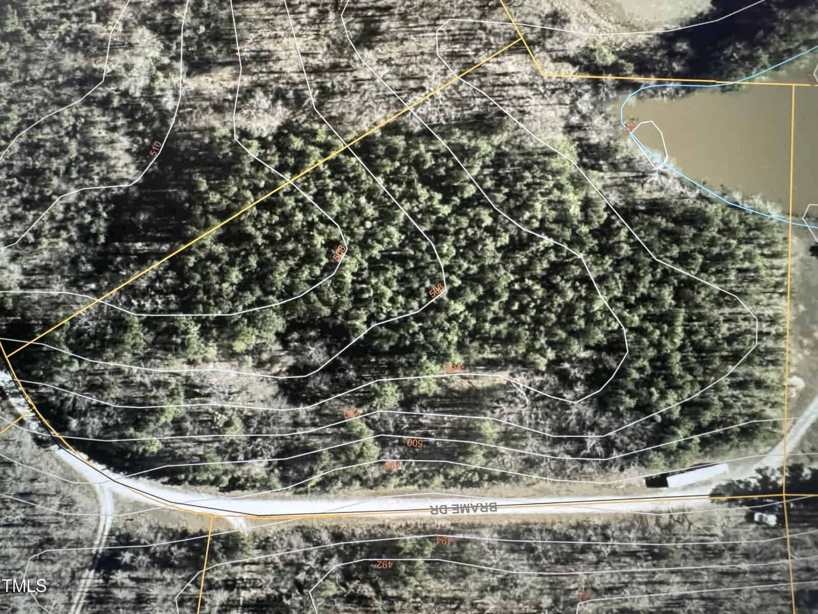 Aerial view of a forested area near Lot 4 Brame Drive, with contour lines marking elevation. A road runs across the bottom of the image in Oxford, and a small body of water is visible at the top right corner. The land is covered with dense trees.