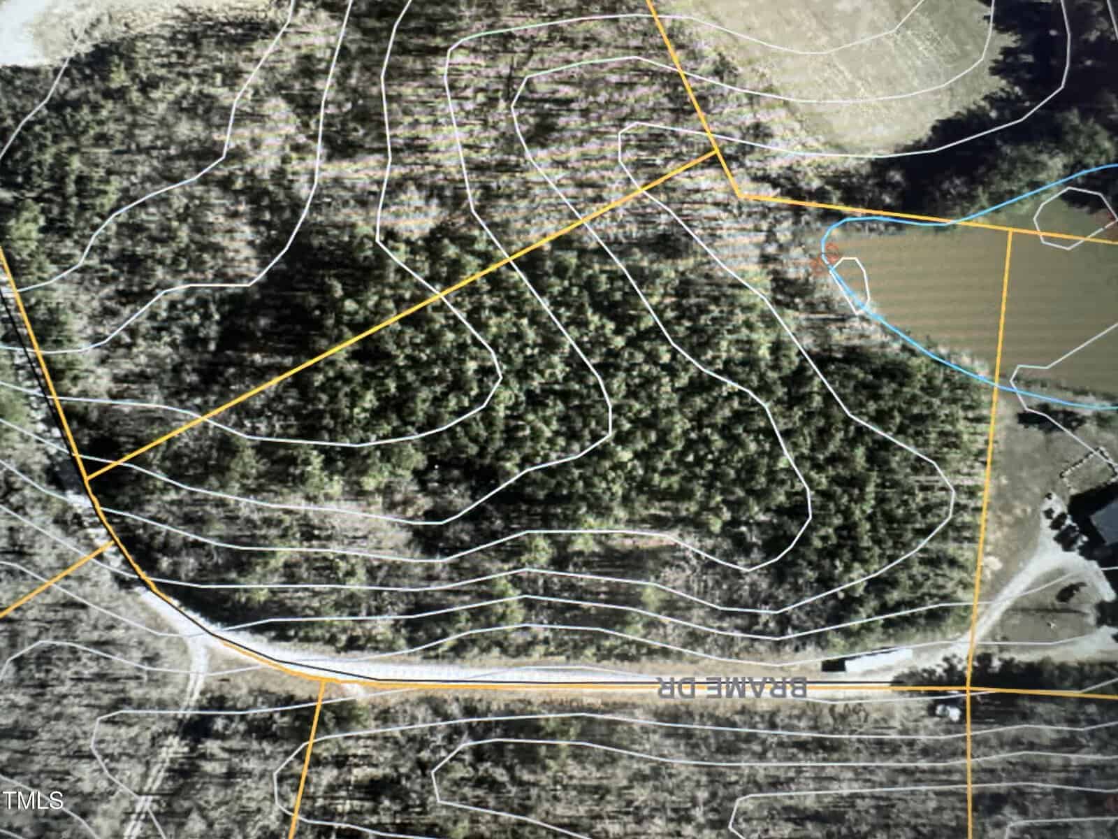 Aerial view of a wooded area with contour lines and property boundaries marked. A road labeled "Prairie Dr" curves through the landscape, next to open land and a few structures.