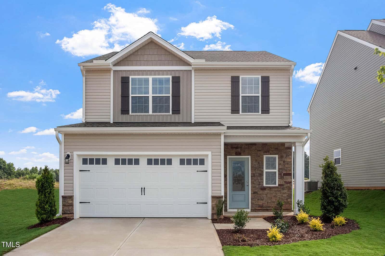 Nestled on 600 Rhino Bend in Oxford, this elegant two-story suburban house boasts beige siding and stone accents. It features a white garage door, two front windows, and a light blue front door. The landscaped front yard has lush grass, shrubs, and a concrete driveway under the clear blue sky.