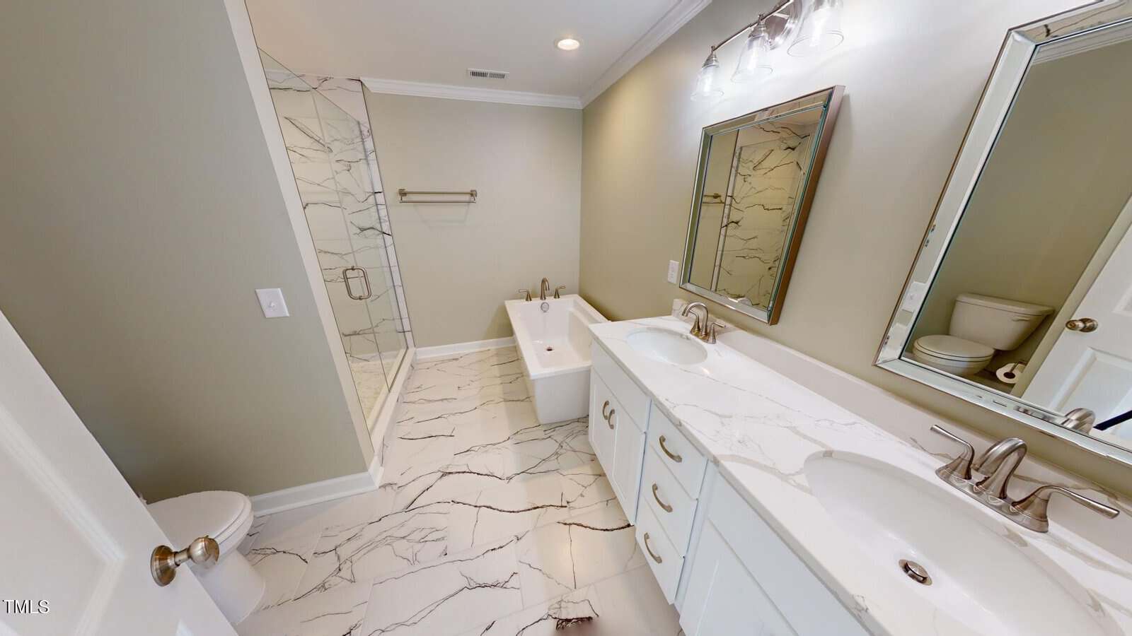 Modern bathroom with marble tile floor, a glass-enclosed shower, a freestanding bathtub, a double-sink vanity with marble countertop, two mirrors, and a toilet in the corner. Neutral wall color and bright lighting.
