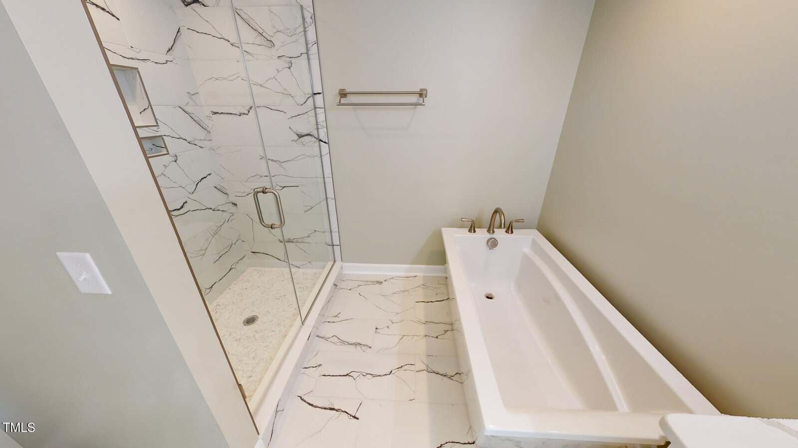 Modern bathroom with a glass-enclosed shower featuring marble-patterned walls and a rectangular bathtub next to it; the floor has matching marble tiles and the walls are painted a light gray.