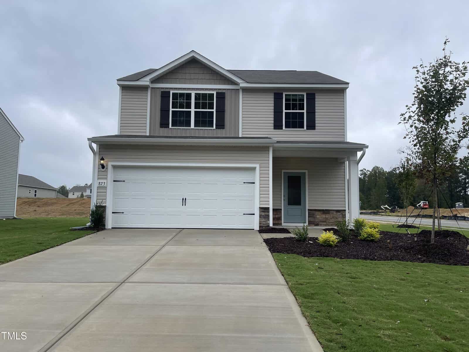 Located at 102 Long Green Way in Oxford, this charming two-story suburban house features a gray exterior with black shutters and a pristine white two-car garage. The front yard is adorned with a well-maintained lawn and a landscaped area of shrubs by the driveway, complemented by a tree on the right side.