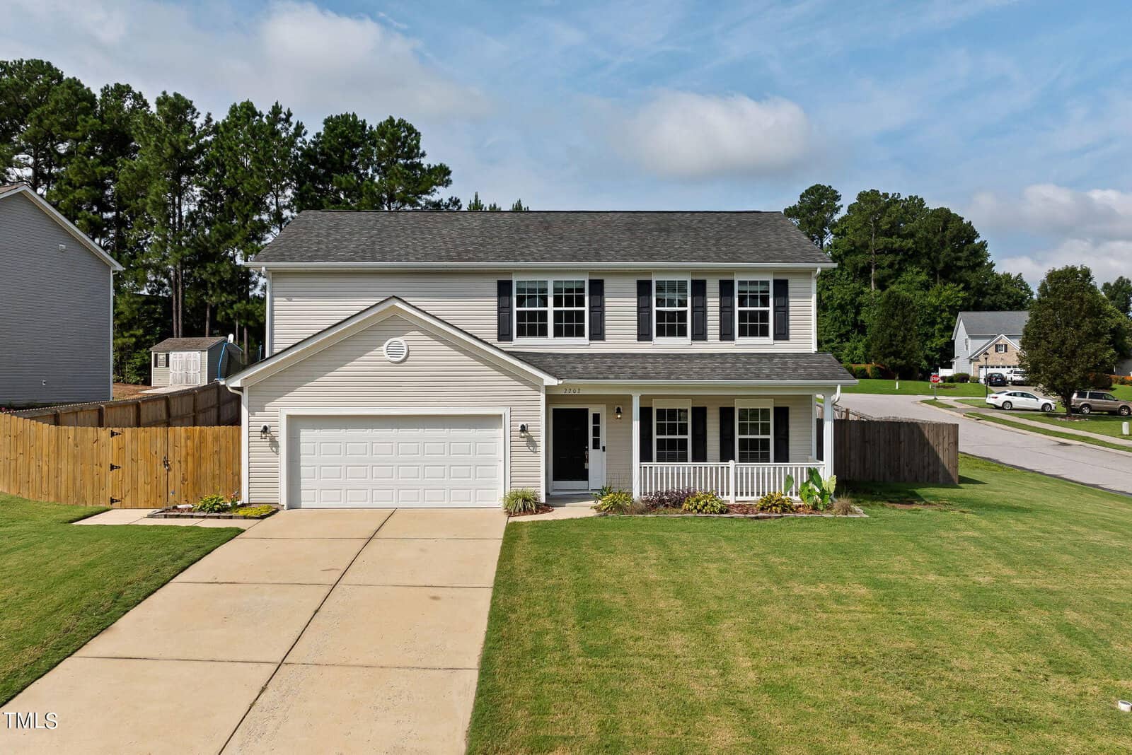 Located at 2202 Hyde Court in Creedmoor, this charming two-story house boasts white siding and black shutters, complemented by a welcoming front porch and an attached garage. Nestled on a spacious, well-maintained lawn with a wooden fence, it fits seamlessly into a neighborhood filled with similar homes and lush greenery.