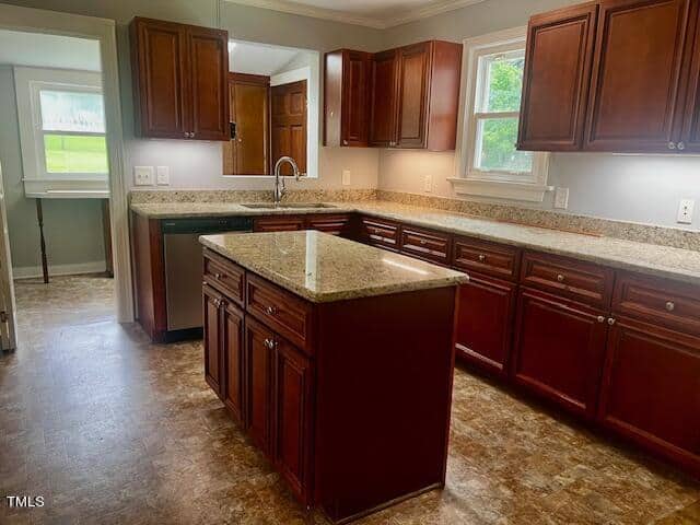 A kitchen featuring wooden cabinets, a central island with a granite countertop, and large windows. The floor has a marble-like design, and stainless steel appliances are visible. Natural light illuminates the space through the windows.