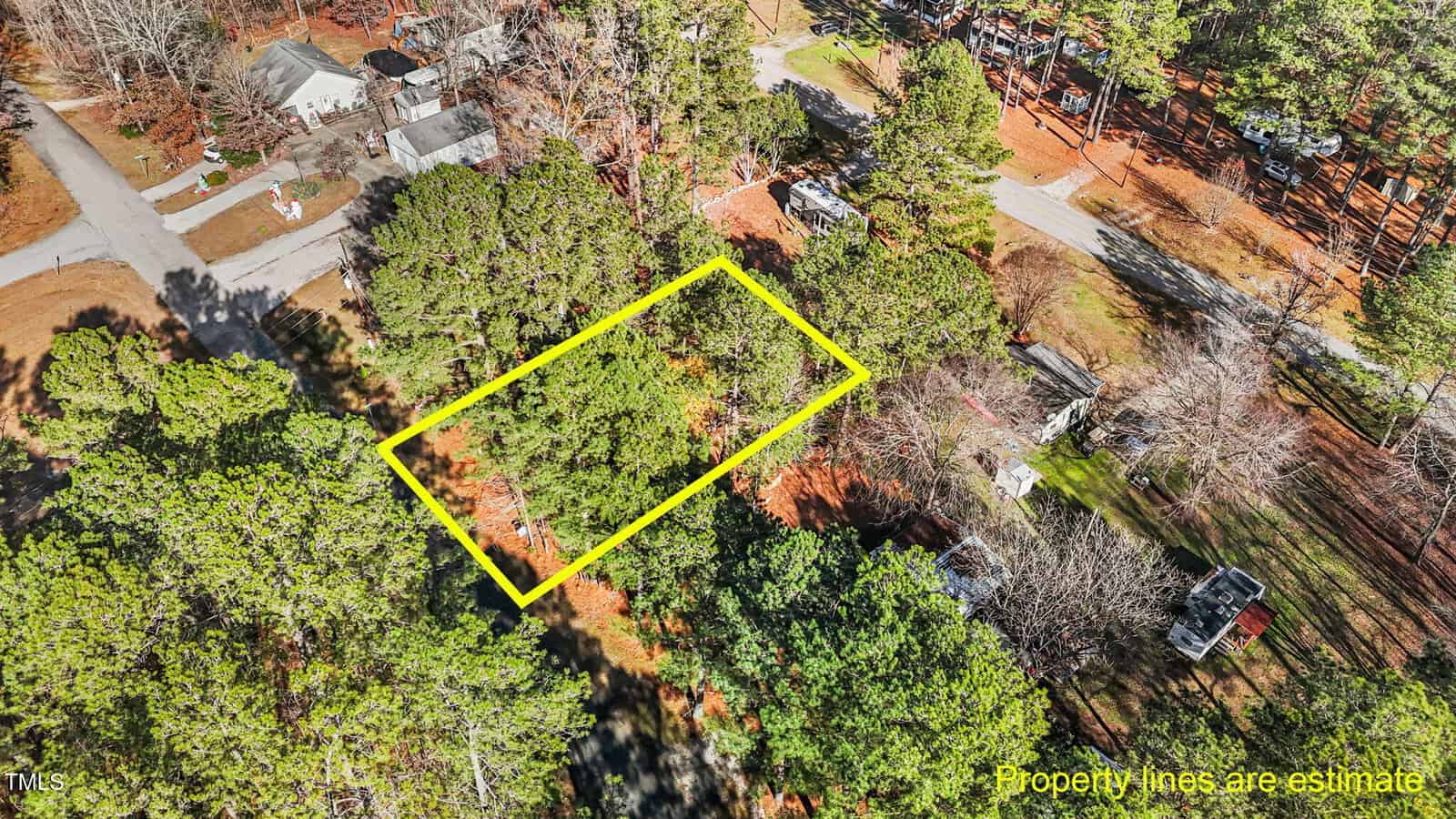 Aerial view of a wooded residential area showing a rectangular lot outlined in yellow, with nearby houses, trees, and roads. Text reads "Property lines are estimate" in the lower right corner.