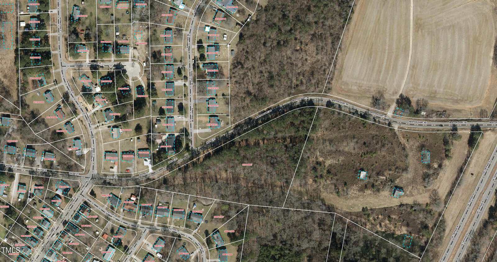 An aerial view of the Henderson residential neighborhood with houses laid out in a grid pattern on the left side, a curved road running through the center, and forested and agricultural areas on the right. A labeled boundary line is visible through the image. The prominent 1106 Water Street stands out.
