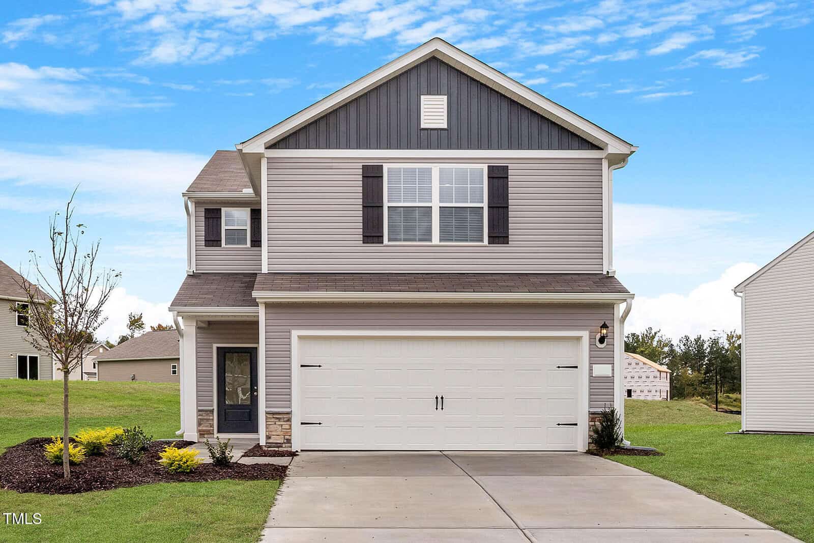 Located at 110 Anaheim Street in Oxford, this two-story house with gray siding and white trim offers a front-facing two-car garage and a cozy porch. The yard showcases new landscaping with small shrubs and lush grass, all set against the backdrop of a clear blue sky.