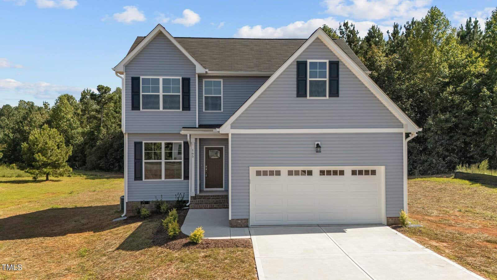 A house with a driveway and trees in the background.