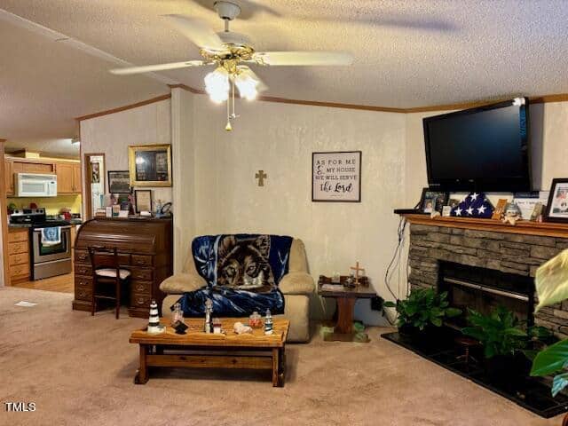 A cozy living room features a sofa with a wolf-themed throw, a wooden coffee table, a fireplace with a TV above, and various decorations. The kitchen is visible in the background. A ceiling fan hangs from the white ceiling, and a framed cross is displayed on the wall.