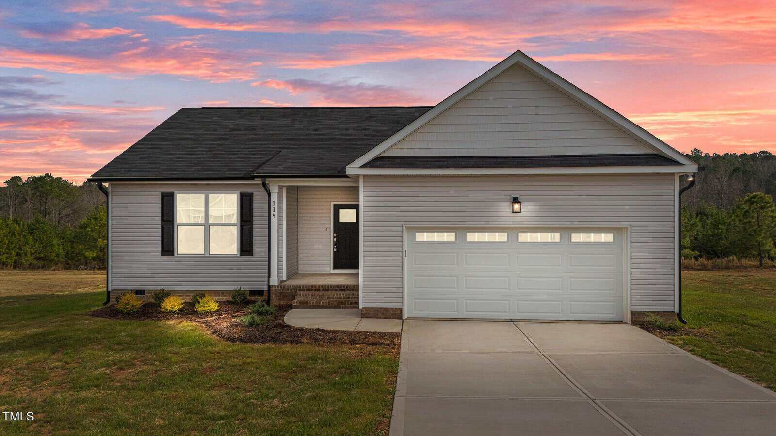 A house with a driveway and a pink and blue sky.