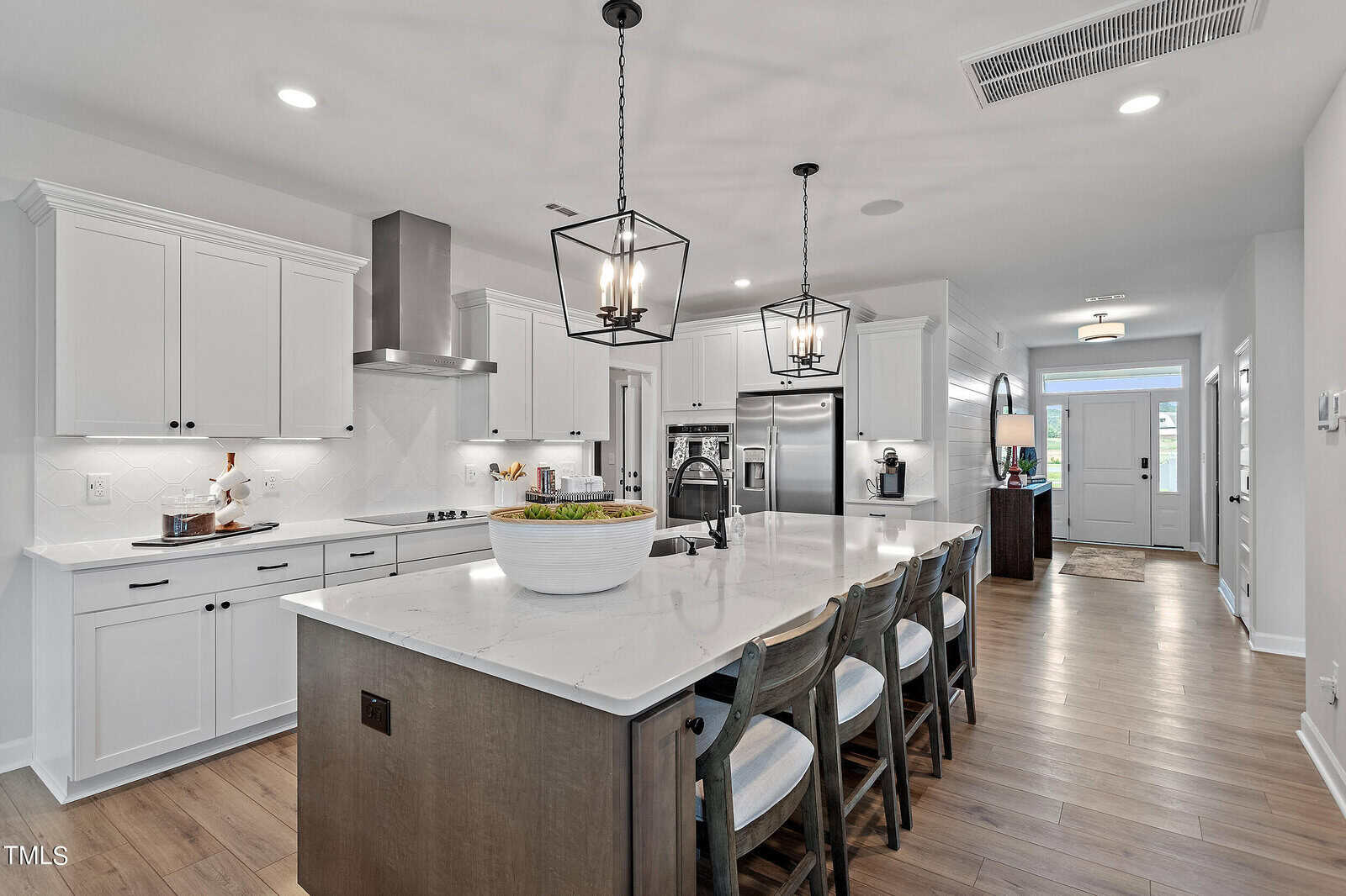A kitchen with a large island and chairs.