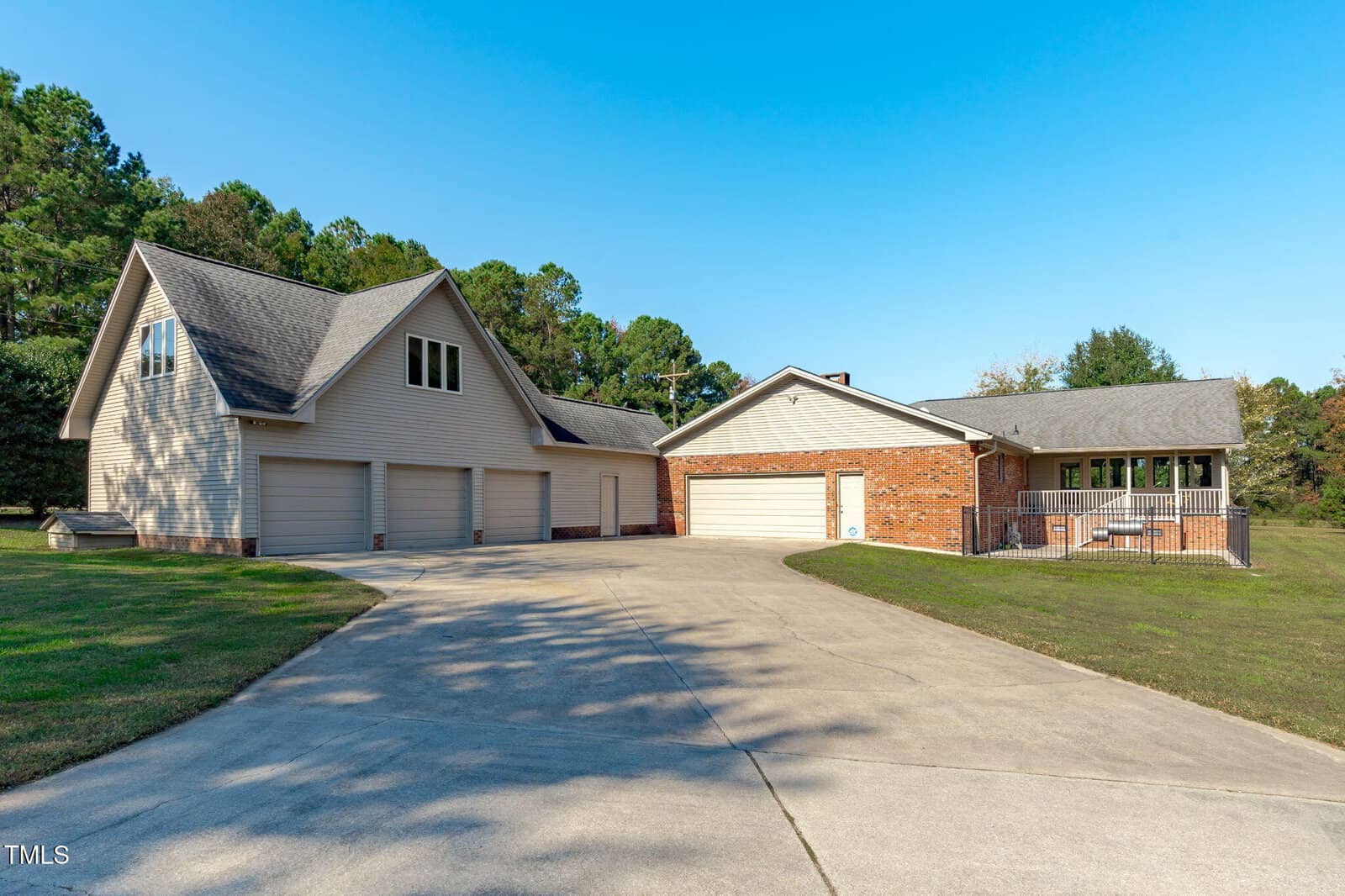 A spacious property with two detached buildings, each with multiple garage doors. The building on the left has four garage bays; the building on the right has two garage bays and a porch. The driveway is wide and paved.