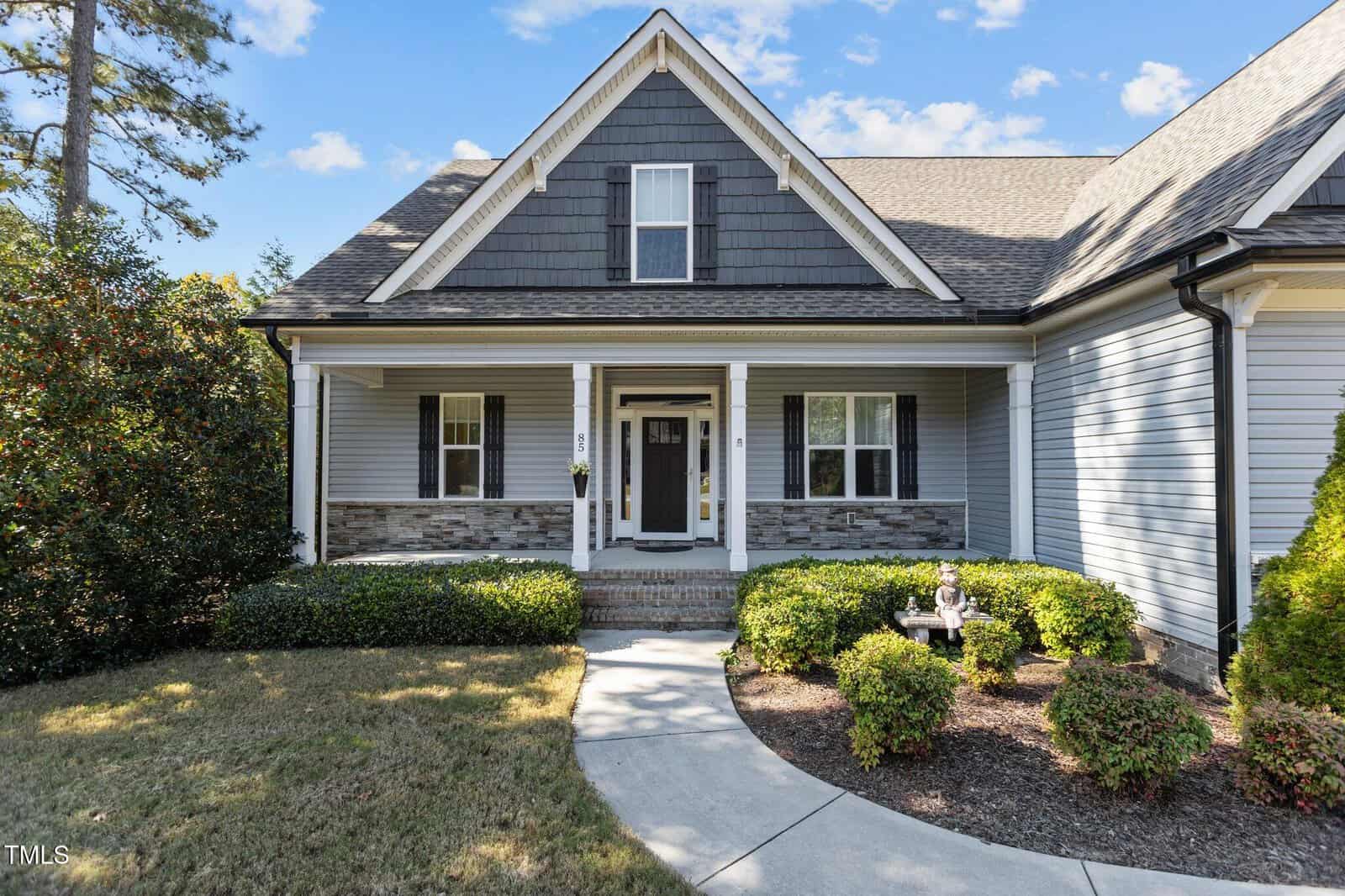 A house with a driveway and bushes.