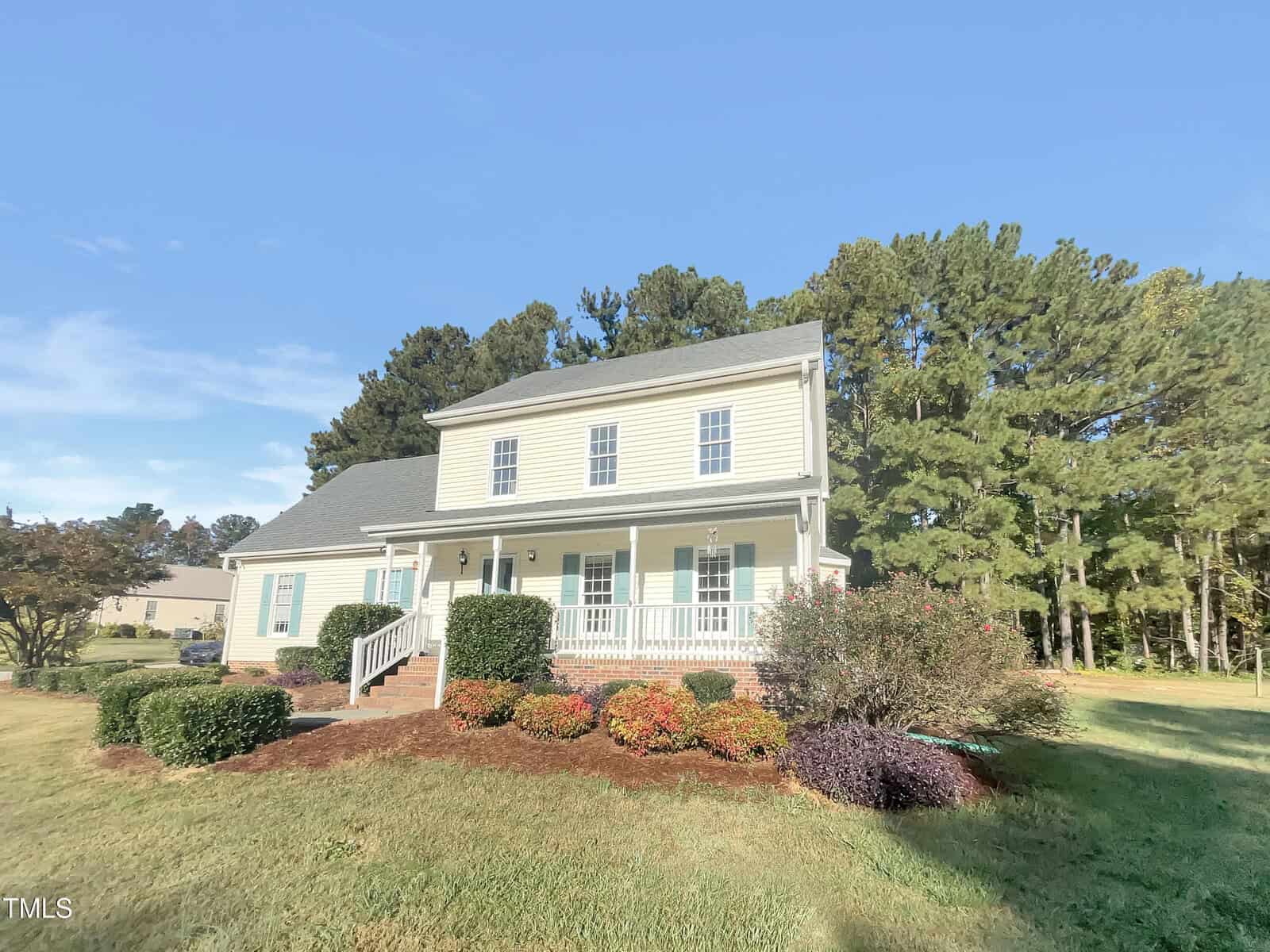 A two-story house located at 3181 Hardie Street in Creedmoor features beige siding and a gray roof, surrounded by a well-maintained lawn and various shrubs. A white front porch with steps leads to the entrance, while trees stand in the background under a clear blue sky.