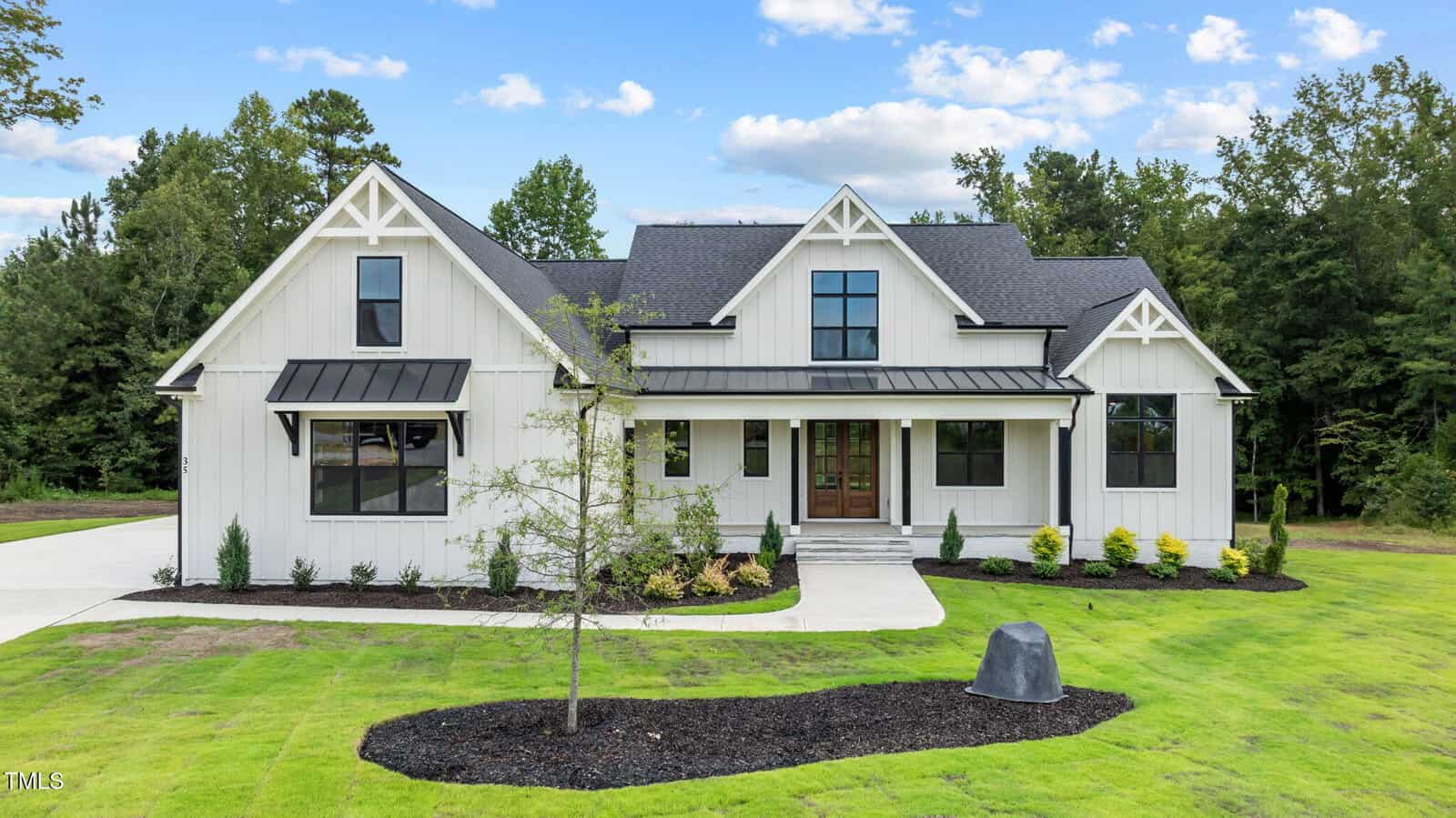 A white house with a lawn and a tree.