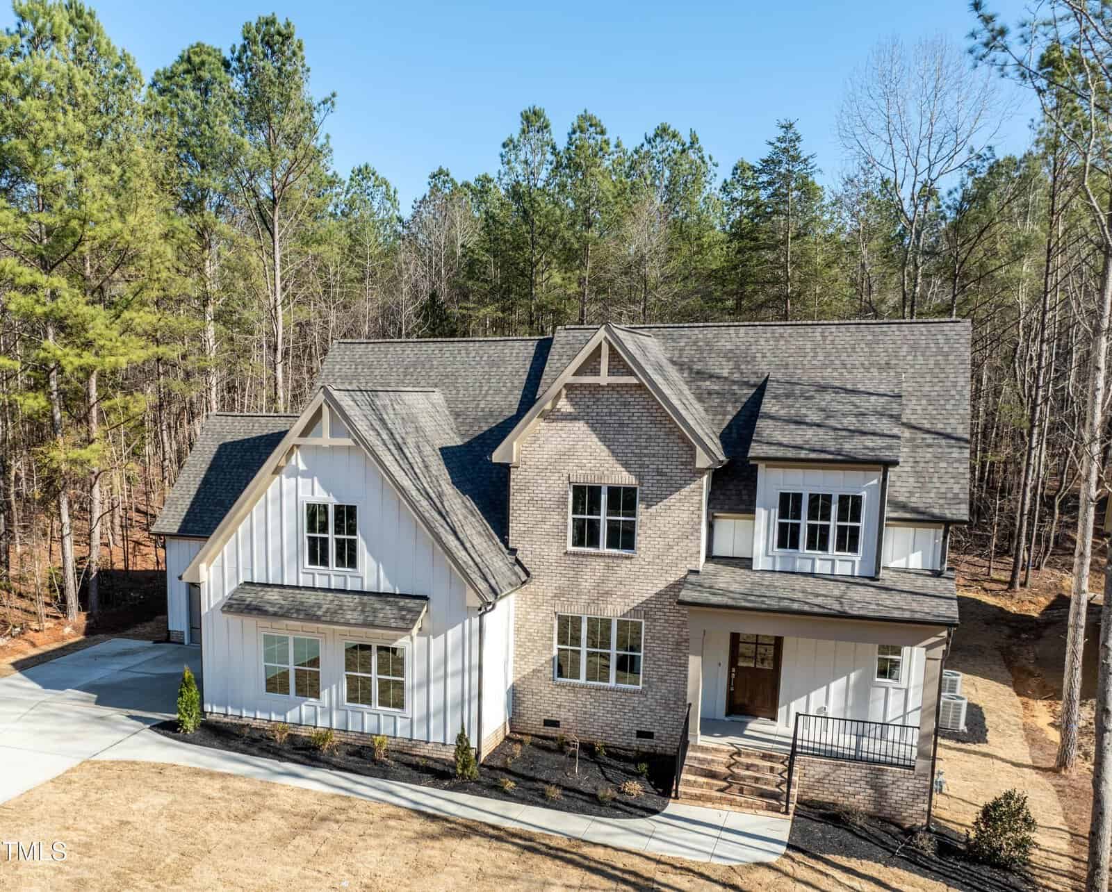 Located at 1226 Red Cedar Court in Youngsville, this two-story modern farmhouse-style home features brick and white siding, large front windows, a covered porch, and a sloped driveway, surrounded by tall pine trees and a dry lawn.
