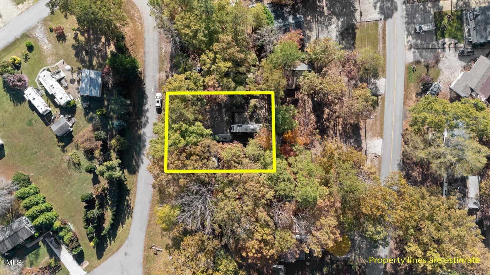 Aerial view of a wooded residential area with a rectangular yellow outline highlighting a property. The property contains a house and surrounding trees. Text in the lower right corner reads, "Property lines are estimation.