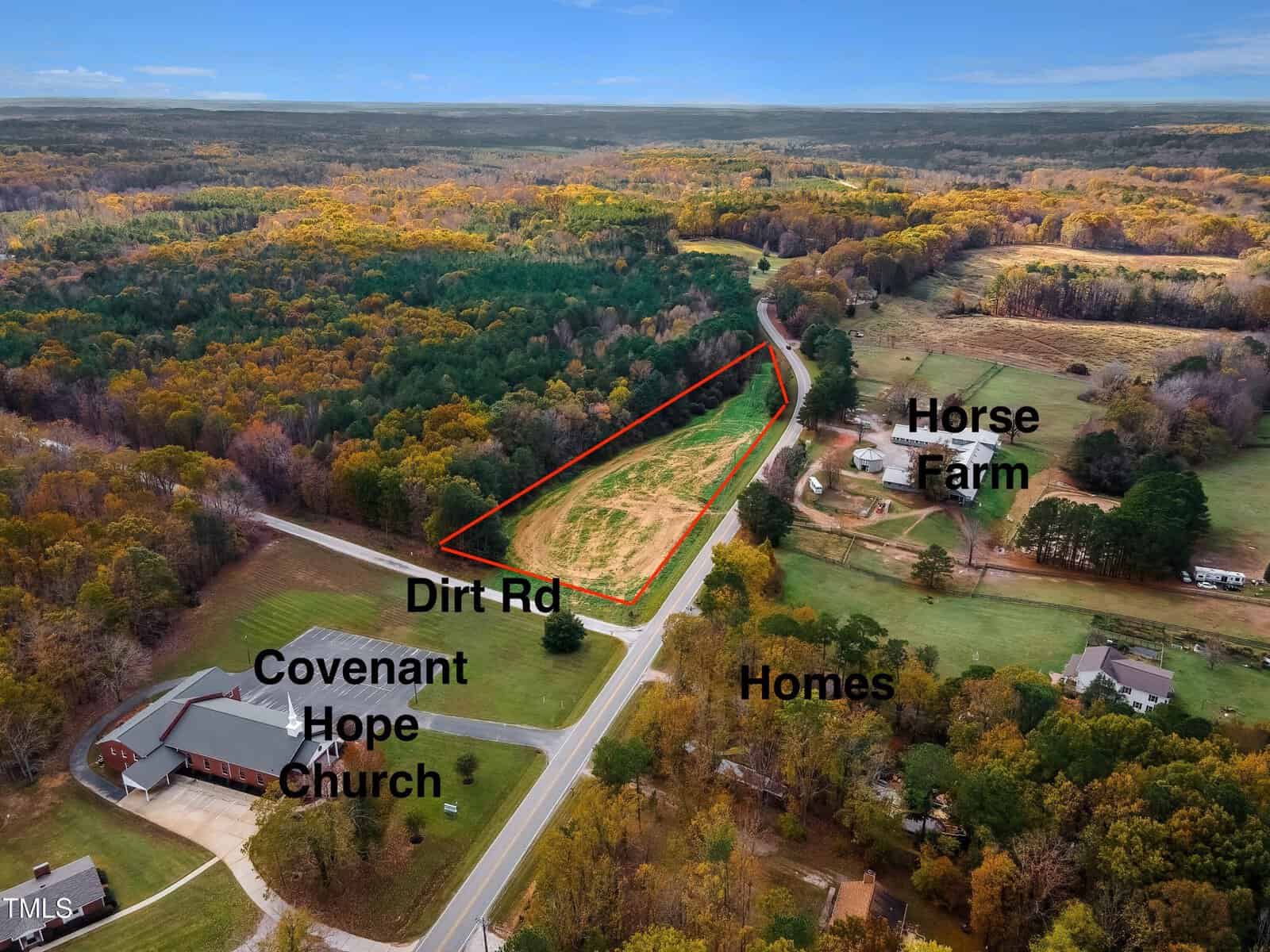 Aerial view of Wake Forest shows a rural area with a dirt road leading to a cleared plot of land outlined in red at 4038 Graham Sherron Road. Nearby, Covenant Hope Church, a horse farm, and several homes are nestled among autumnal trees and fields.
