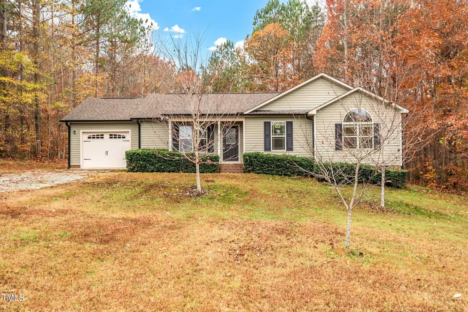 Located at 2221 Irvin Street in Oxford, this charming one-story house features light siding and a dark roof. A single-car garage complements the large window. Surrounded by trees with autumn foliage under a partly cloudy sky, a lush grassy lawn welcomes you home.