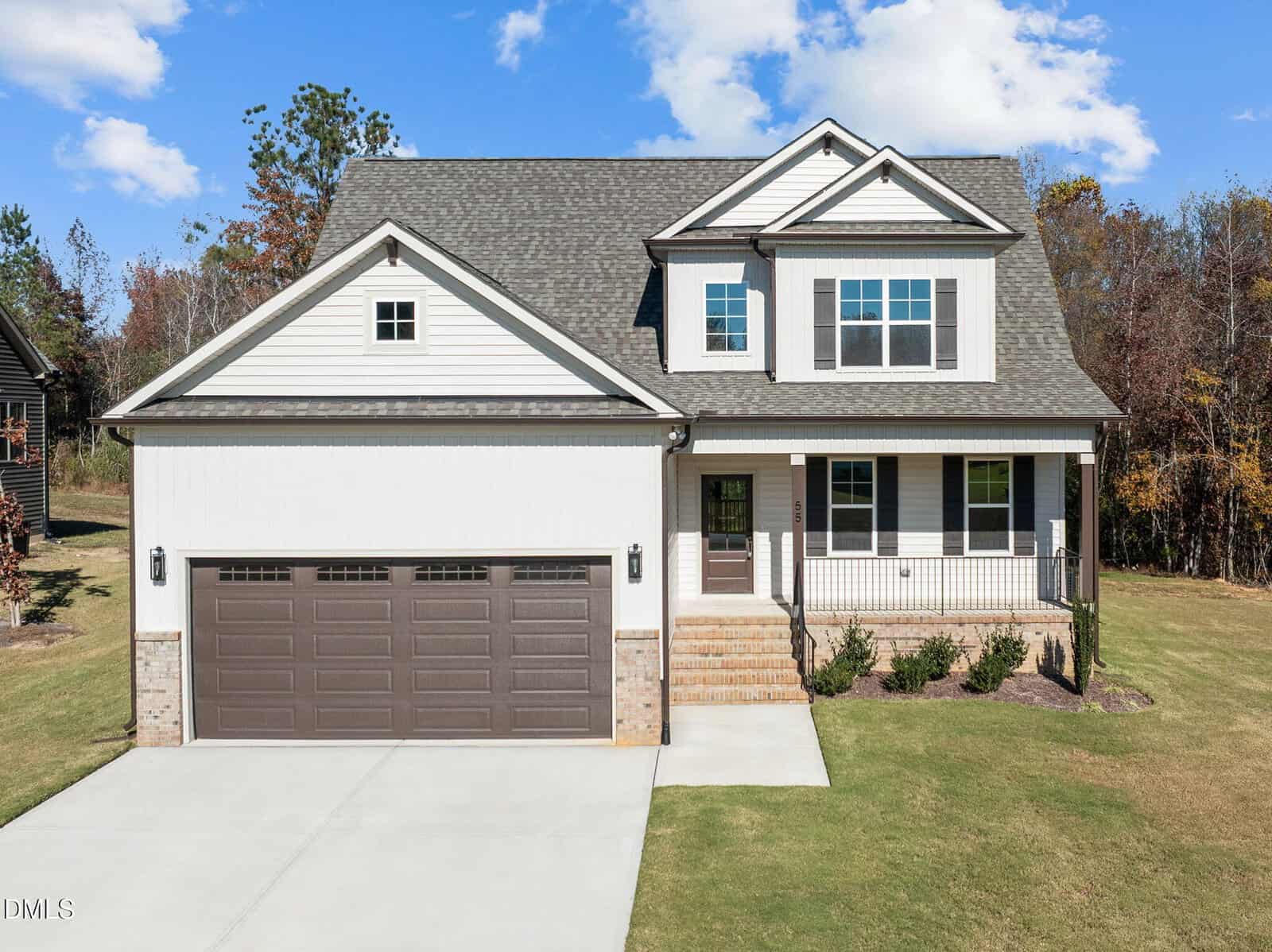Charming two-story suburban home at 55 Basil Court, Franklinton, with light-colored siding, dark shutters, a covered front porch, and double garage. Enjoy a lush yard with green grass, landscaped bushes, and trees beneath a blue sky.