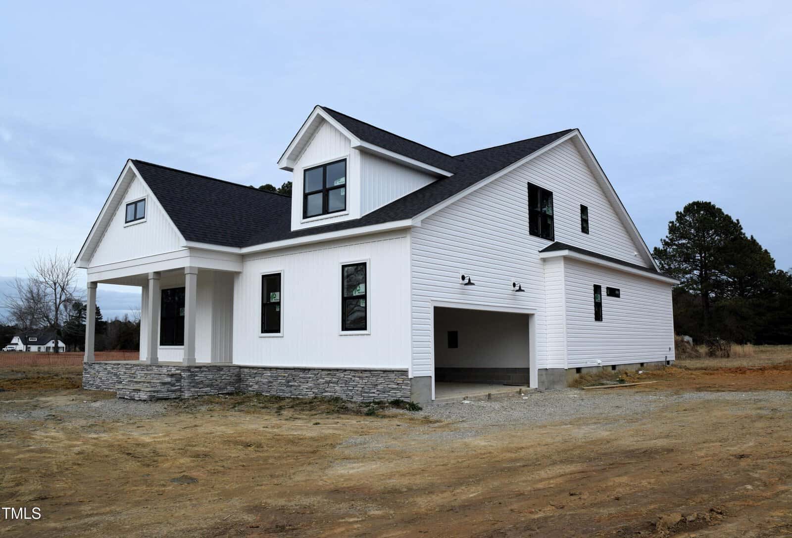 A newly constructed white two-story house with black trim, gray stone accents, and an attached two-car garage sits on a bare dirt lot at 1590 NC 96 in Franklinton under a cloudy sky.
