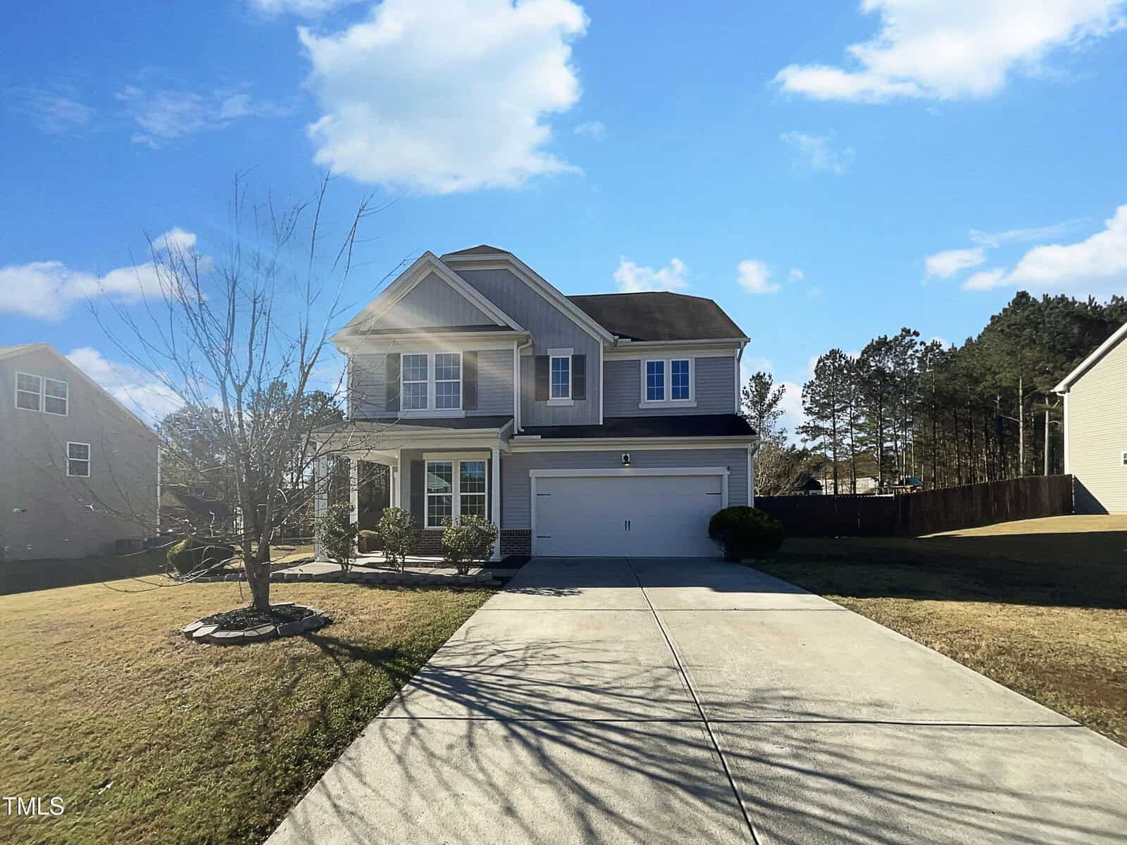 A two-story suburban house at 720 Forrest Lane in Creedmoor features a double garage. The front yard hosts a leafless tree with minimal landscaping. Set in a residential area of similar homes, it stands under a clear blue sky.