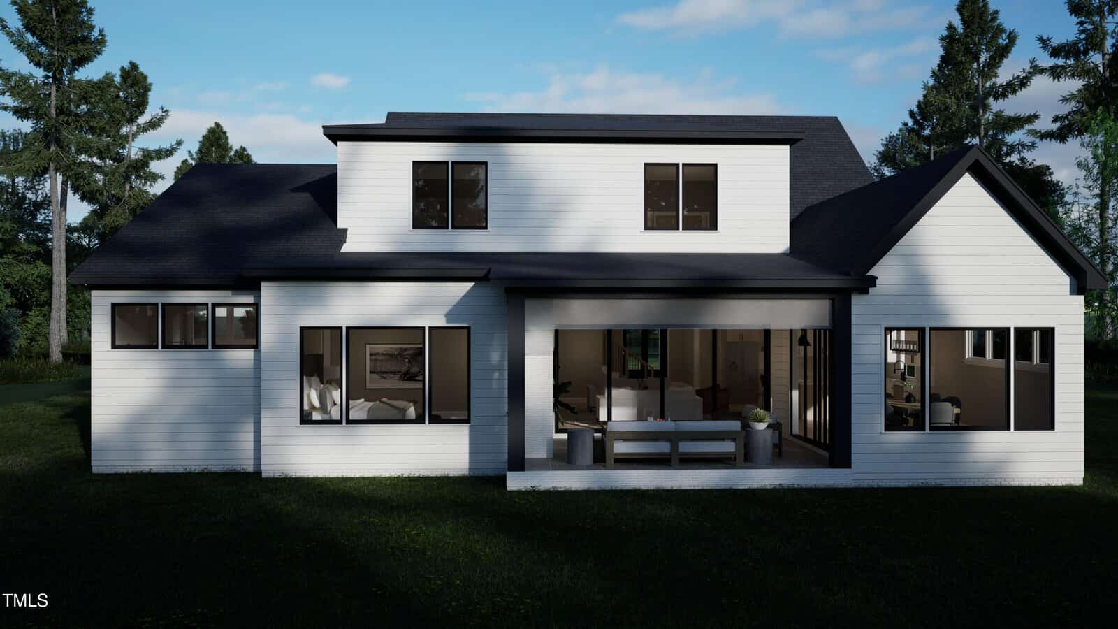 A modern two-story white house with large black-framed windows, dark roof, and an open patio area with outdoor furniture, set on a grassy yard surrounded by trees under a partly cloudy sky.