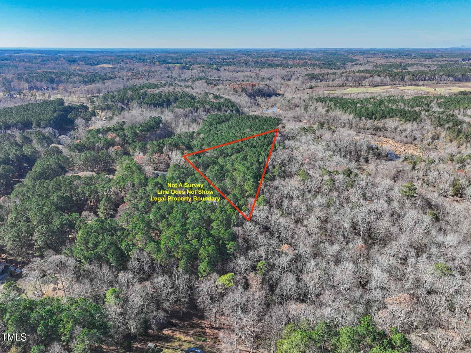 Aerial view of a forested area with a triangular red outline marking a section of trees. Text inside the triangle says, “Not A Survey! Line Does Not Show Legal Property Boundary.”.