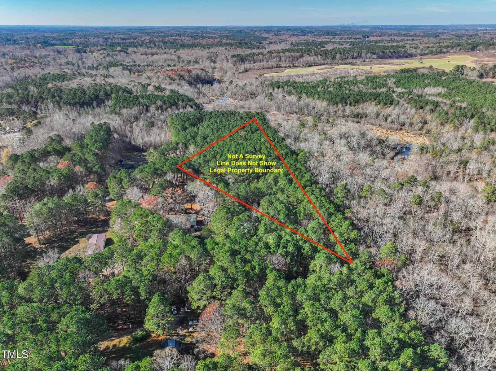 Aerial view of a wooded area with a red triangle outlining a section of land labeled "Not A Survey, Line Does Not Show Legal Property Boundaries"; surrounding land has dense trees and sparse clearings.