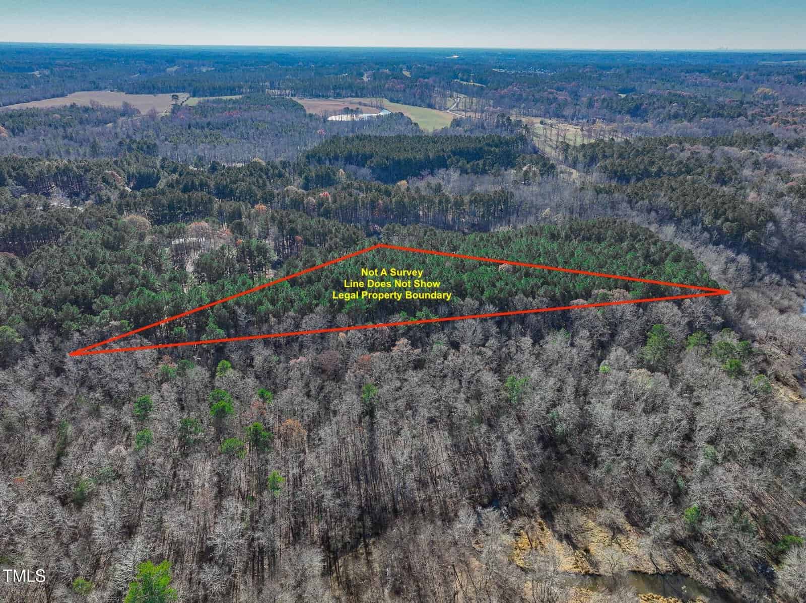 Aerial view of a wooded area with a red outlined triangle indicating approximate property boundaries. Yellow text states, "Not A Survey, Line Does Not Show Legal Property Boundary." Surrounding forest and fields are visible.