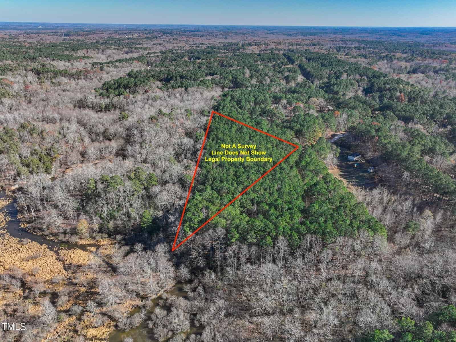 Aerial view of a forested area with a triangular red outline marking part of the land. Yellow text states, “Not a Survey. Lines Do Not Show Legal Property Boundaries.” River and scattered trees visible.