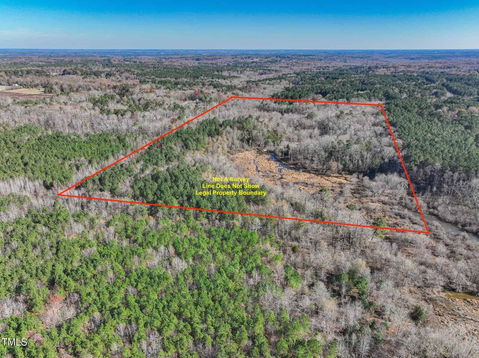 Aerial view of a wooded landscape near Louisburg with a cleared area and an orange outline marking the approximate property boundaries at 0 Flat Rock Church Road; text indicates the line is not a legal boundary.